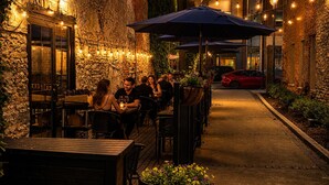 An outdoor dining area with stone walls, tables, chairs, and string lights.