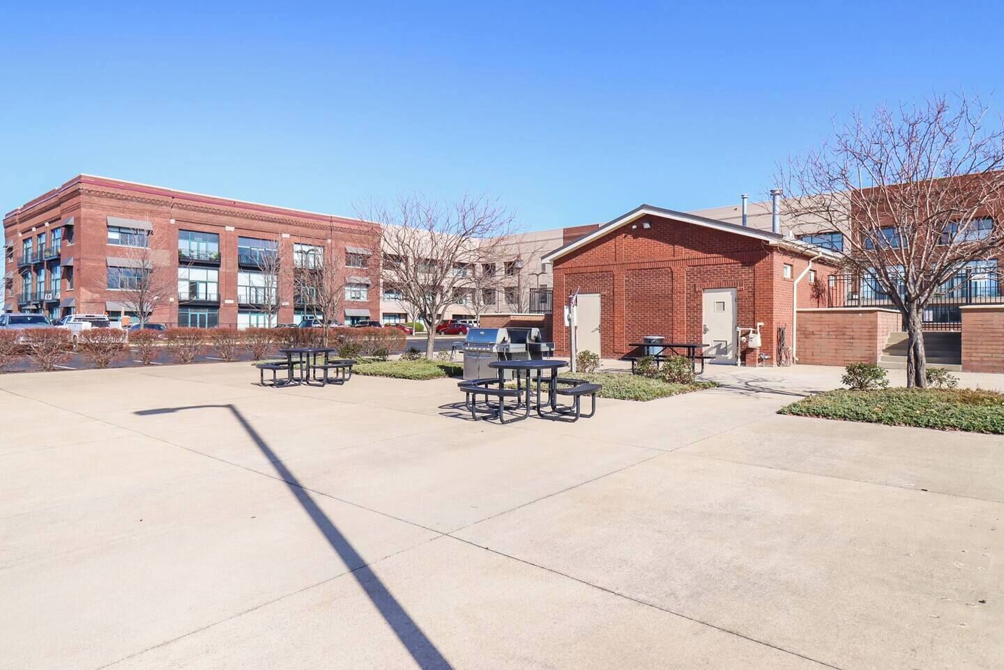 A courtyard with picnic tables and a brick building.