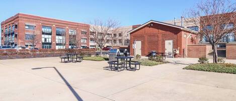 A courtyard with picnic tables and a brick building.