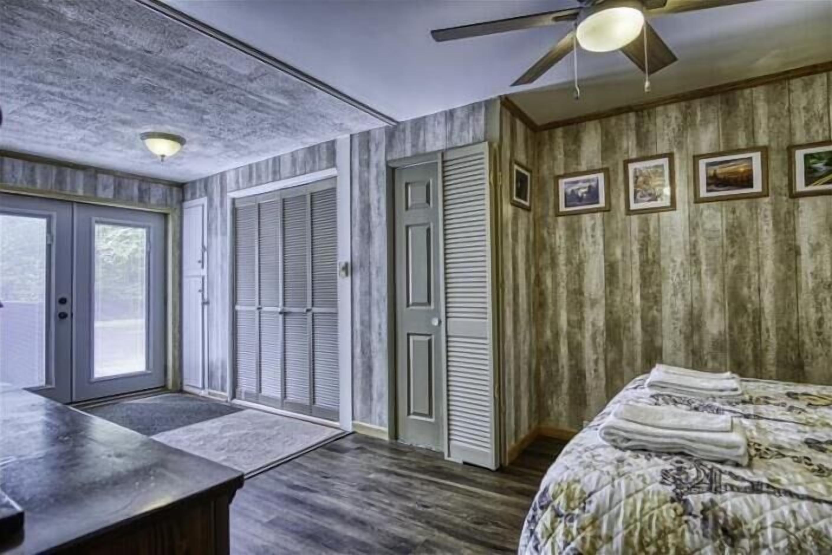 A bedroom with a bed, a desk, and a ceiling fan.