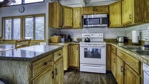A kitchen with wooden cabinets, a white stove, a microwave, and a large window. - SS12-Bass, Blue Gill, and Catfish Pond! Hot Tub! Dolly Sods Access! (Davis)