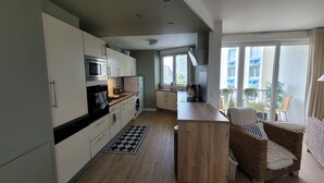 Une cuisine moderne dotée d’un îlot central, d’appareils électroménagers intégrés et offrant une vue sur le balcon.