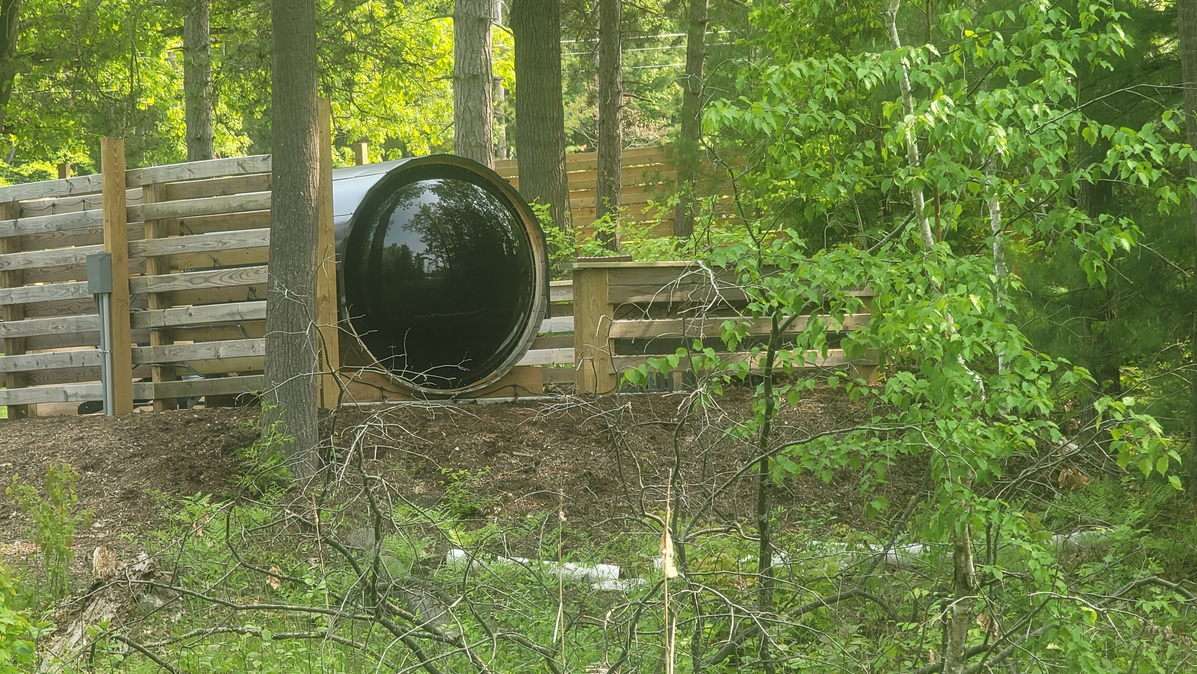 Une clôture en bois avec un grand tonneau noir au centre.