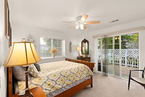 A bedroom with a bed, a ceiling fan, a lamp, a dresser, a mirror, and a view of the outdoors through a sliding glass door. - COMFY-COZY, Quiet, EV car CHARGER, GARAGE, Recliner  (Grants Pass)