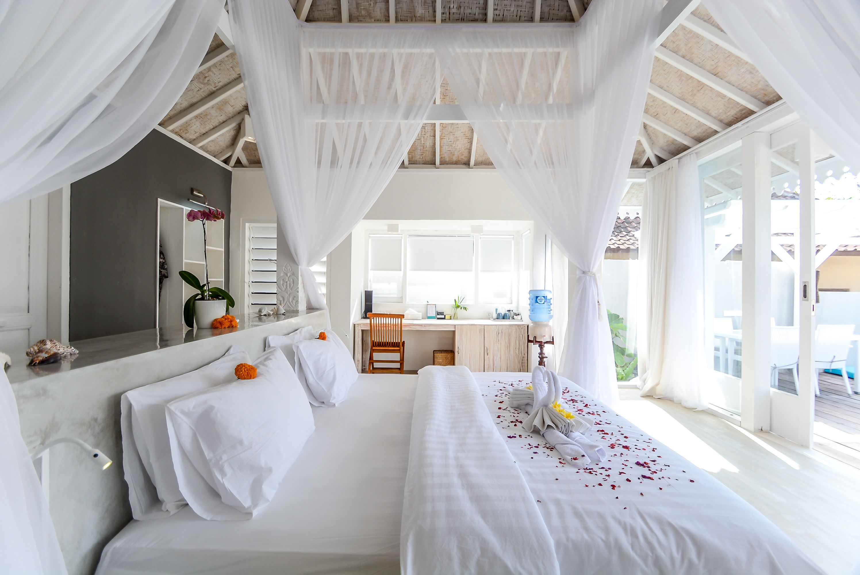 A hotel room with a large bed, a desk, and a view of the outdoors.