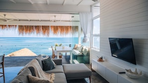 A modern living room with a large TV, comfortable seating, and a view of the ocean. - Mahi Mahi Villa & Suites (Pecatu)