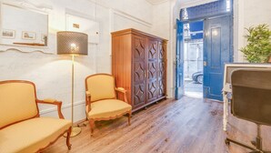 A room with wooden flooring, a large cabinet, two chairs, a floor lamp, and a blue door leading outside. - Chiado 44 (Lisbon)
