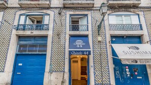 A building with blue doors and balconies, a sushi restaurant sign, and a shop named "Chiado 44". - Chiado 44 (Lisbon)