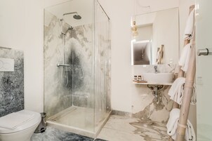 Un baño moderno con ducha de vidrio, lavamanos de mármol y un inodoro.