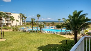 A pool area with lounge chairs and palm trees, overlooking a beach and ocean. - CRC 1210 - Second Story Condo with Great Ocean Views (St Augustine)