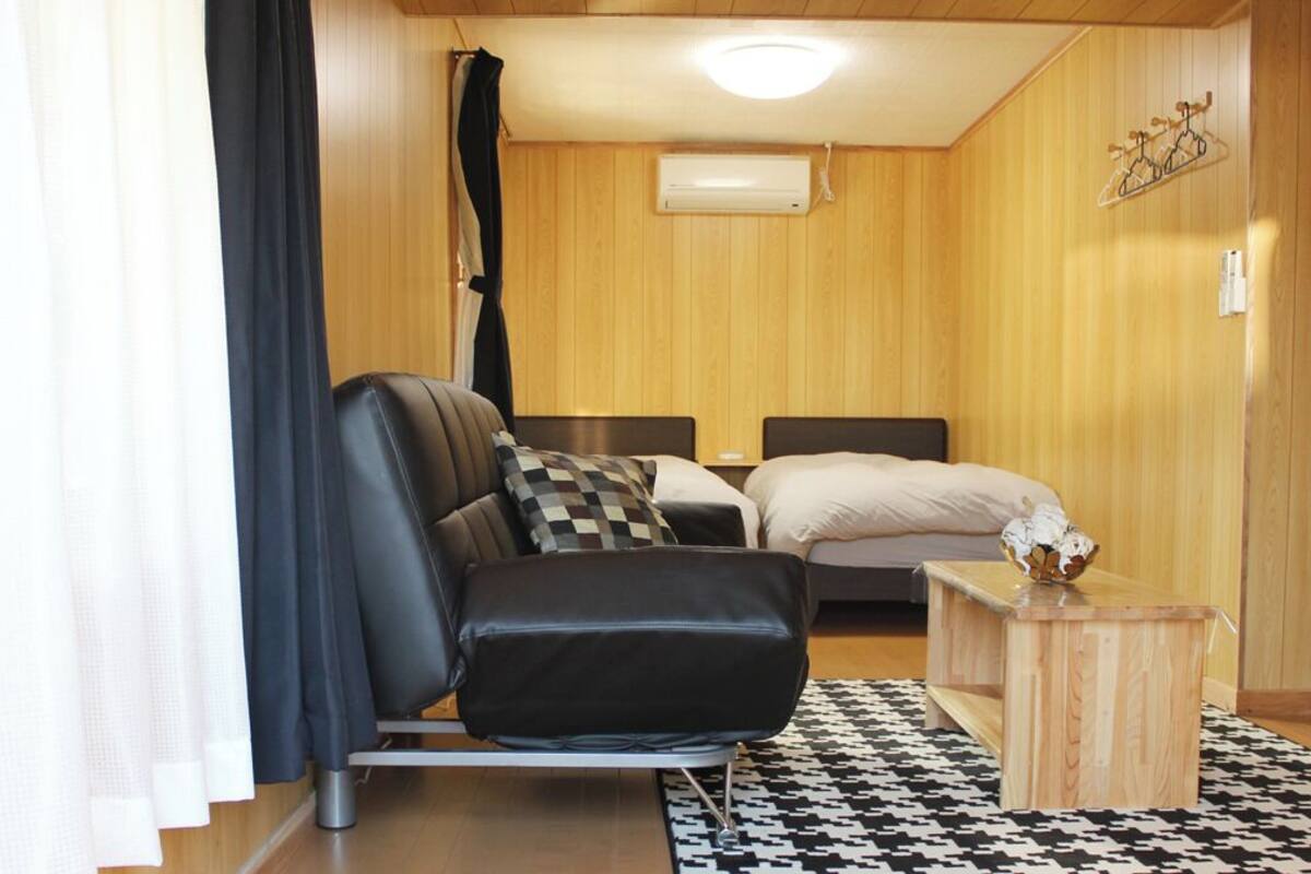 A room with a bed, a chair, a small wooden table, and a patterned rug.