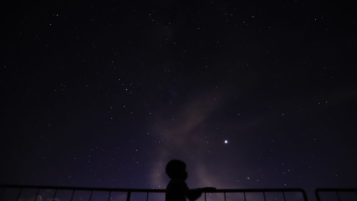 Un ciel nocturne constellé d’étoiles, observé depuis derrière une rambarde.