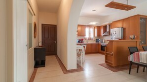 A modern kitchen with wooden cabinets, a central island, and a dining area with a table and chairs. - Naxos "Asty" walking distance to everything! (Naxos)