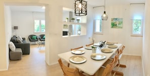 A modern dining area with a white table set for six, surrounded by wooden chairs.