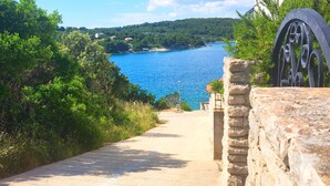 A pathway leading to a body of water, surrounded by greenery and stone walls. - Villa Sol - private heated pool & 30m from the sea (Necujam)