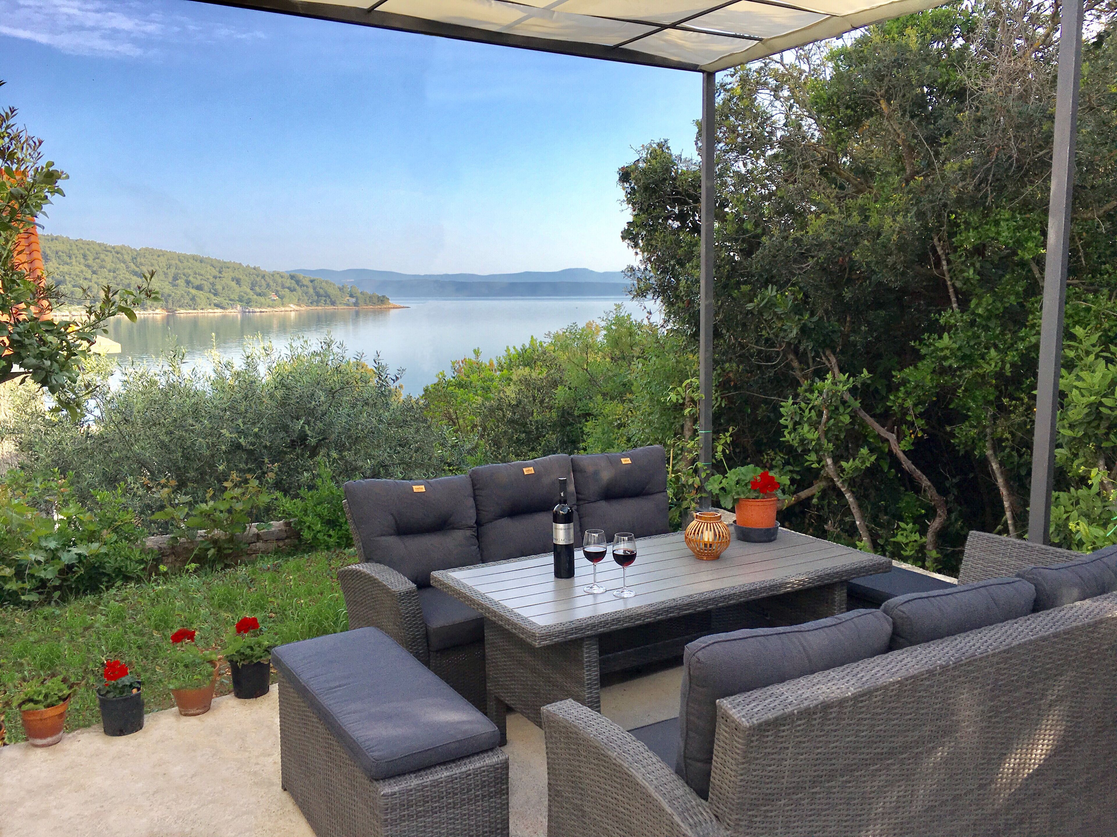 Patio esterno con mobili in vimini, un tavolo e piante in vaso.