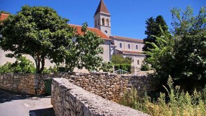 A historic building with a prominent tower and a stone wall in the foreground. - Villa Sol - private heated pool & 30m from the sea (Necujam)