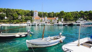 A marina with several boats docked, a building with a tower, and a hillside with trees. - Villa Sol - private heated pool & 30m from the sea (Necujam)
