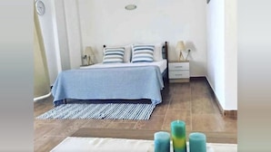 A bedroom with a bed, nightstands, and a rug. - Grande Blue Suites with private bay (Rhodes)