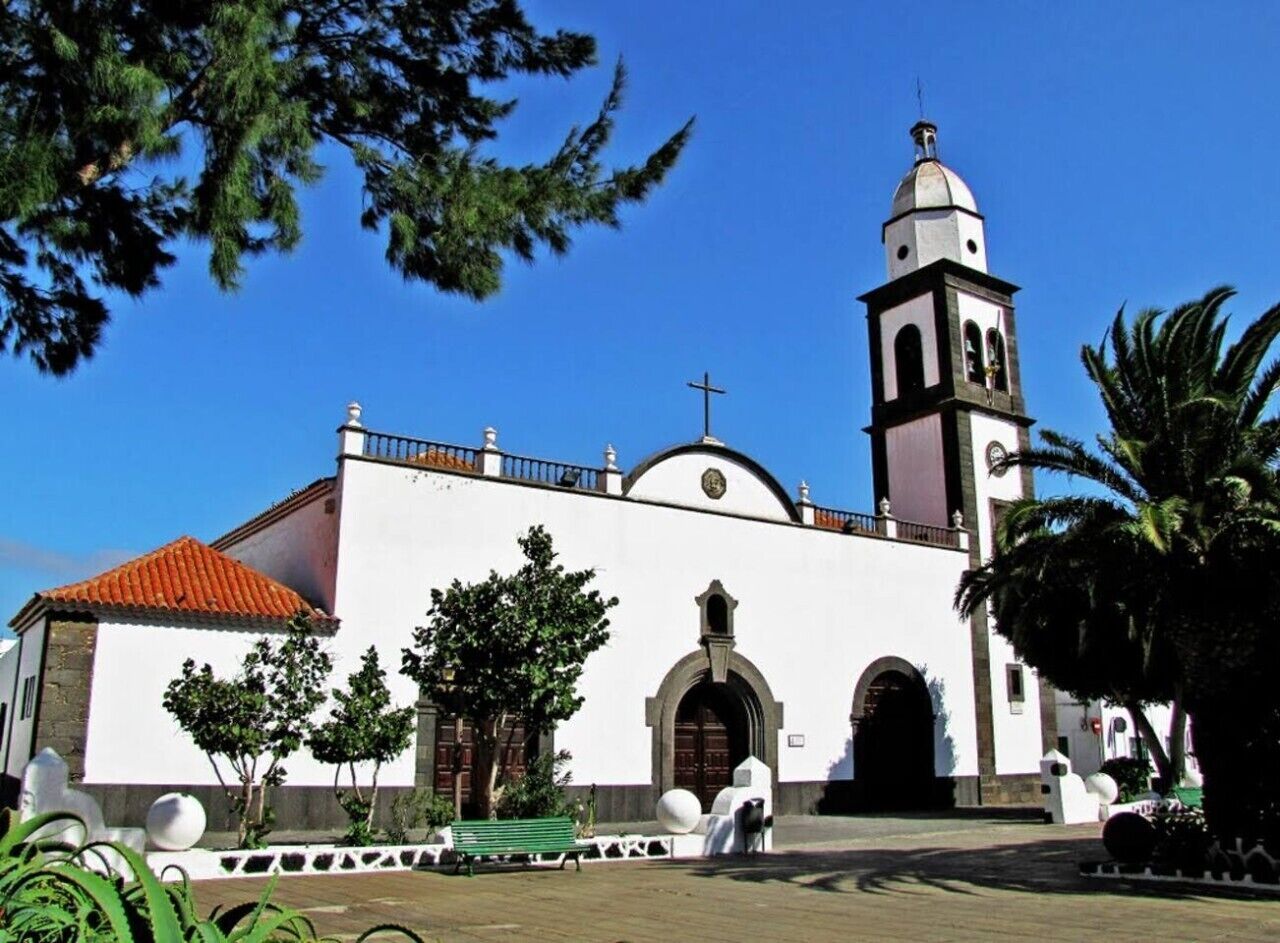 Eine Kirche mit Glockenturm, Rundbogenportal und einem Ziegeldach.