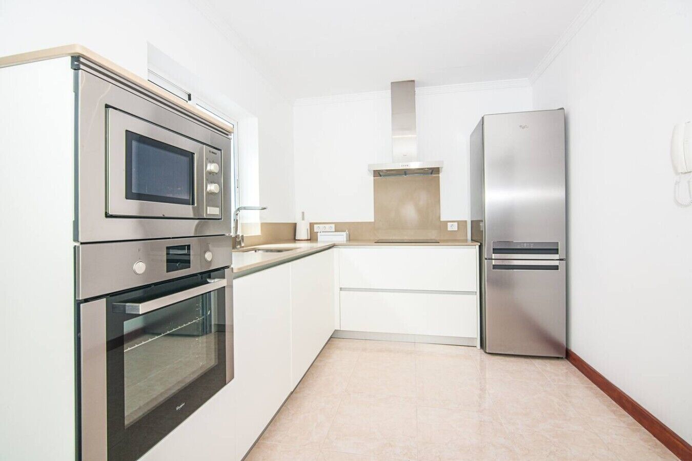 A compact kitchen with stainless steel appliances, including a microwave, oven, and refrigerator.