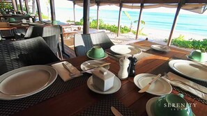 Ein Esstisch mit Blick auf Strand und Meer.