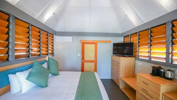Una habitación de hotel con una cama, televisión, cómoda de madera y kitchenette.