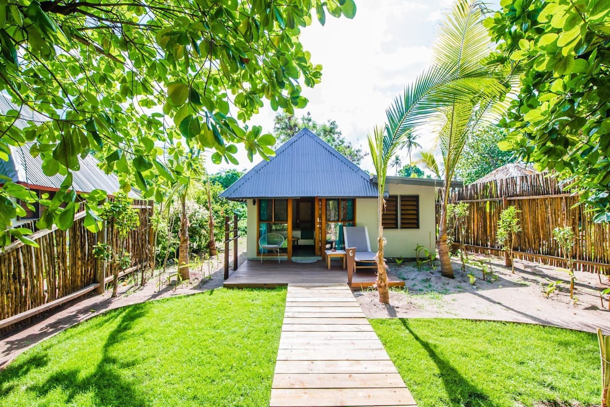 A house with a blue roof, a wooden deck, and a garden with a pathway leading to the entrance.