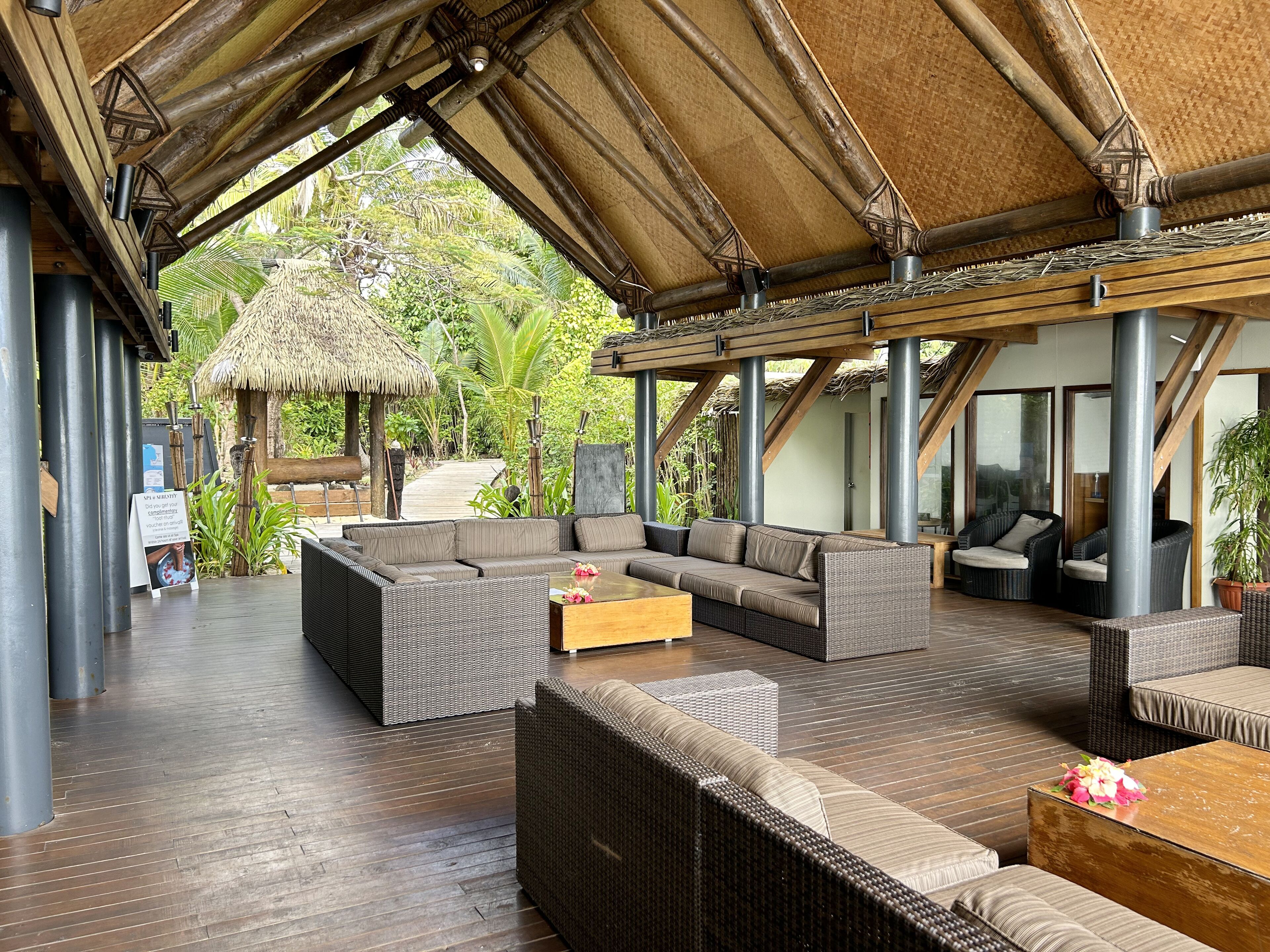 A covered outdoor seating area with wicker furniture and a thatched roof structure.