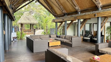 A covered outdoor seating area with wicker furniture and a thatched roof structure.