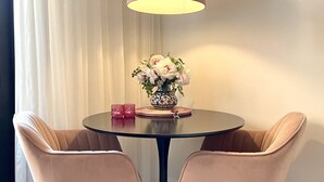 Ein Essbereich mit einem runden Tisch, zwei Stühlen, einer Blumenvase und einer Hängelampe.