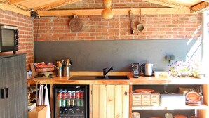 Eine rustikale Küche mit Backsteinwand, Holzbalkendecke und einem eingebauten Kühlschrank.