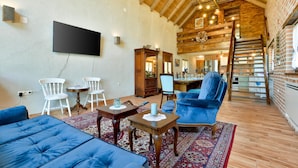 A cozy living room with a fireplace, a TV mounted on the wall, and a staircase leading to an upper level.