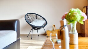 A modern living room with a black wireframe chair, a wicker basket, a glass of wine, and a vase with flowers on a wooden table. - Lovely home in Sv.Martin na Muri with sauna (Sv.Martin na Muri)
