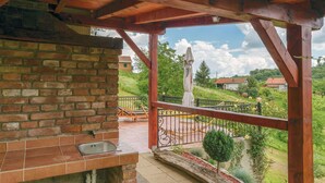 A covered outdoor area with a brick wall, a sink, and a view of a rural landscape with houses and greenery. - Lovely home in Sv.Martin na Muri with sauna (Sv.Martin na Muri)