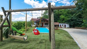 A wooden swing set, a small pool, and a house with a red roof. - Lovely home in Sv.Martin na Muri with sauna (Sv.Martin na Muri)