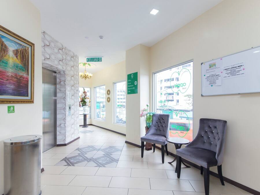 A hotel lobby with a reception desk, a painting, a whiteboard with a menu, and a view of the street outside.