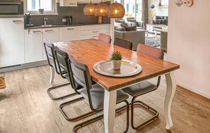 Enjoy meals in this stylish dining area with a wooden table and metal chairs, surrounded by a modern kitchen and a large window.