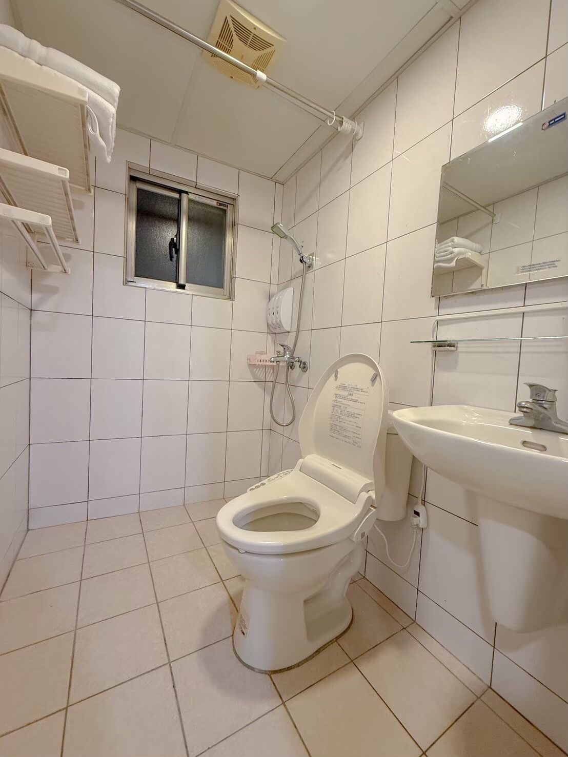 Un baño con inodoro, ducha, lavamanos y ventana.