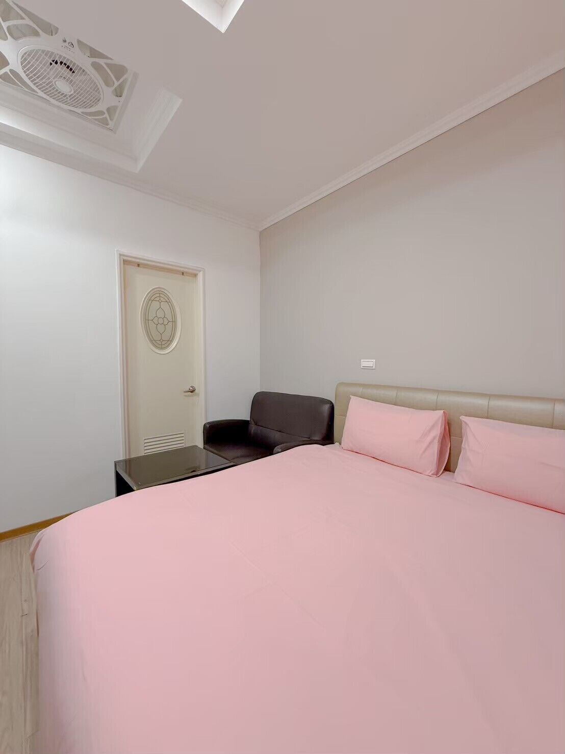 Ein Schlafzimmer mit Bett, Stuhl, Schreibtisch und Deckenventilator.
