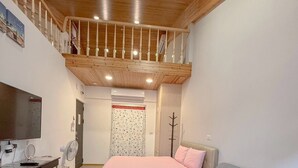 Un grand espace de vie doté d’un haut plafond, d’un balcon, d’un lit, d’un canapé et d’une petite table.