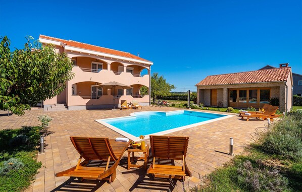 Uma casa de dois andares com piscina, área de estar externa e jardim.