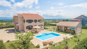 Una casa de dos pisos con piscina, mobiliario exterior y vistas al campo.