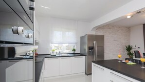 Una cocina moderna con armarios blancos, electrodomésticos de acero inoxidable y encimera negra.