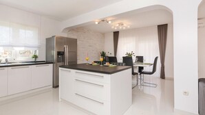 Una cocina moderna con una isla central, electrodomésticos de acero inoxidable y un comedor con mesa y sillas.