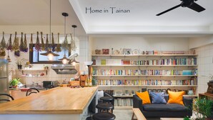 Una cocina moderna con una isla de madera, taburetes de bar y una estantería llena de libros.