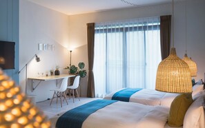 A hotel room with a bed, a desk, chairs, a lamp, and a large window with curtains.