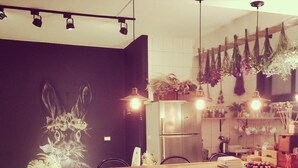 Una cocina moderna con una mesa de comedor de madera, taburetes negros, plantas colgantes y un refrigerador.