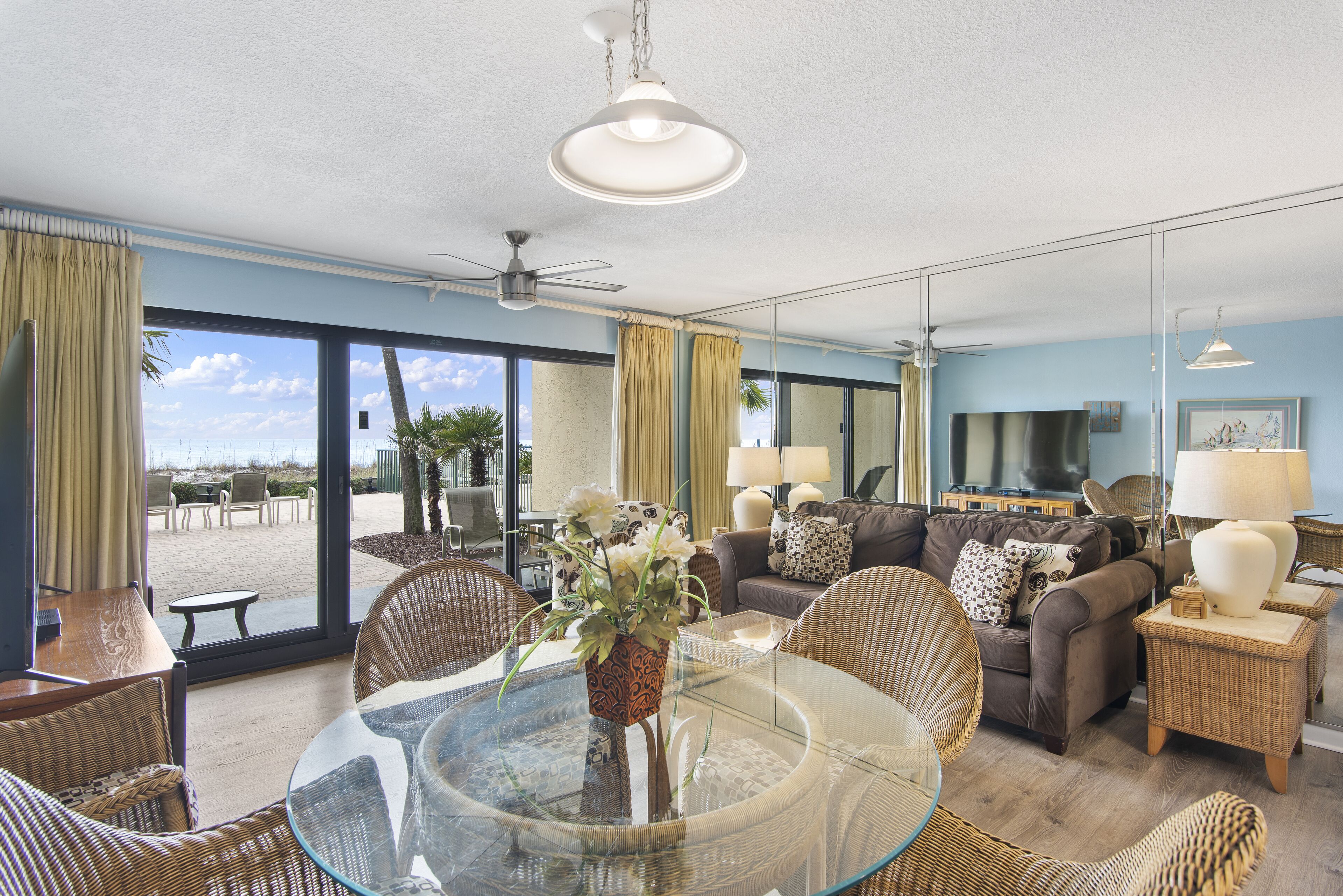 A spacious living room with a glass table, wicker furniture, a sofa set, and a view of the outdoors.