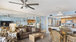 A modern living room with a sofa, coffee table, and wicker chairs. There is a kitchen area with a refrigerator and microwave. - 112- Fabulous BEACH FRONT condo. Destin Beach Club (Destin)